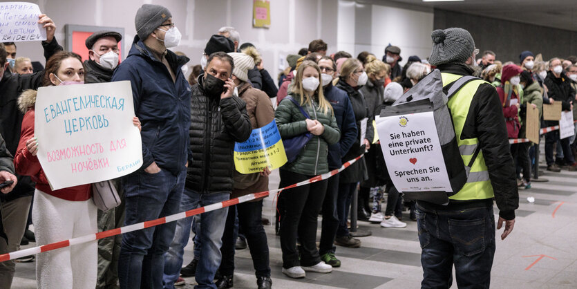 Menschen am Berliner Hauptbahnhof halten Schilder hoch, auf denen Hilfsangebote wie Unterkünfte für Flüchtlinge aus der Ukraine notiert sind.