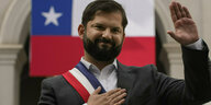 Chiles Präsident Gabriel Boric winkt Anhängern vor der Nationalflagge