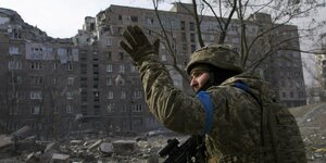 Ukrainischer Soldat vor zerstörtem mehrstöckigen Wohngebäude
