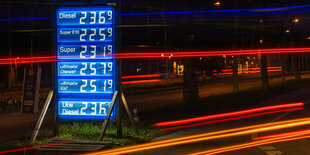 Blaue Anzeigetafel an einer Tankstelle, rote Streifen vom Verkehr gezogen