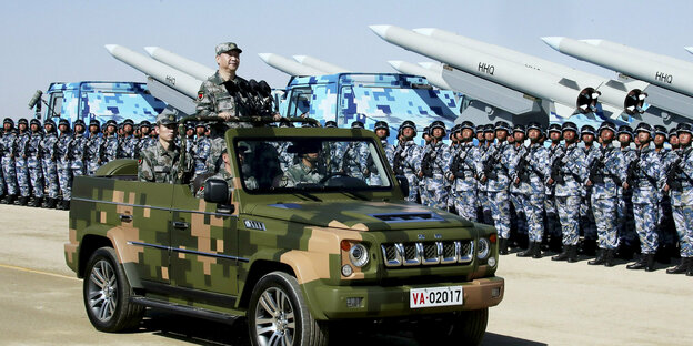Präsident Xi Jinping in einem Jeep vor Soldaten und Raketen.