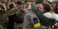 Eine Frau umarmt ihren Freund, der eine Uniform trägt