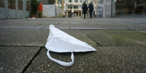 Das Foto zeigt eine FFP2-Maske, die - offenbar verloren oder weggeworfen - auf der Straße liegt.
