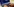 Eine Hand tippt auf einem Laptop, auf dem Code zu sehen ist