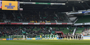 Spieler und Fans im Weserstadion, auf einer Anzeigetafe steht: "Stand with Ukraine"