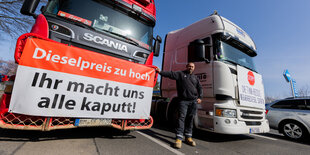 Ein LKW-Fahrer steht vor stehenden LKWs auf einer Autobahn