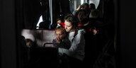 Eine Frau sitzt in einem vollen Zug mit einem Kind auf dem Arm