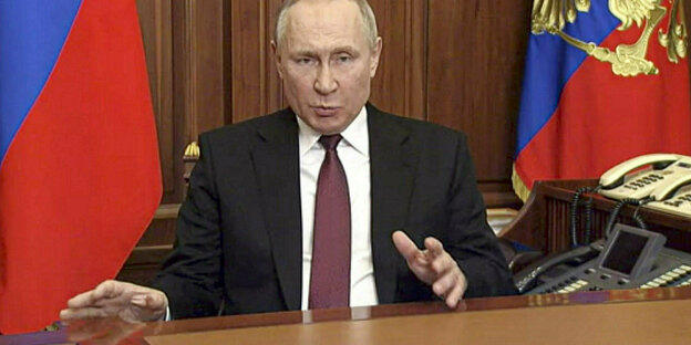 Der russische Präsident spricht vor offiziellen Flaggen zu seiner Nation