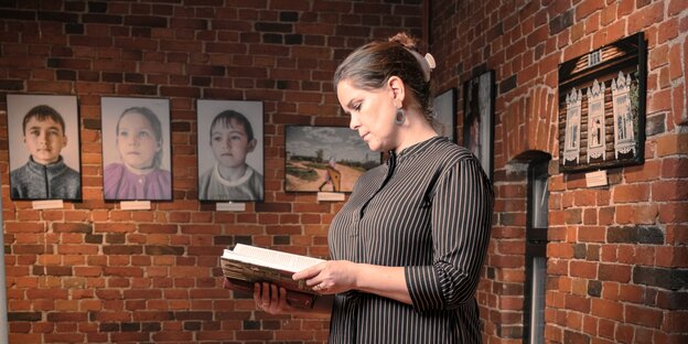 Niina Sinkko steht in einer Ausstellung und liest in einem Buch