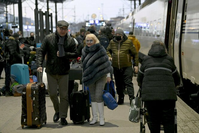 Menschen mit Gepäck laufen über einen Bahnsteig, eine Frau hat sich einen Pelz umgeschlungen