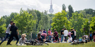 Menschen grillen in einem Park, dahinter der Fernsehturm