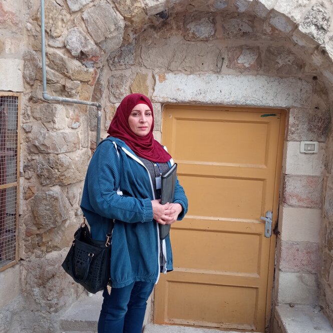 Eine Frau mit blauer Jacke und rotem Kopftuch: Manal jabari in Hebron