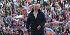 Vladimir Putin vor Publikum mit russischen Flaggen