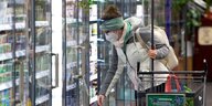 Frau vor Kühlregal mit FFP2-Maske und Einkaufswagen