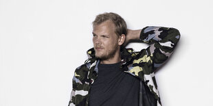 Der Künstler Avicii sitzt auf einem Stuhl, schaut direkt in die Kamera. Er verstarb 2018