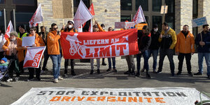 Streikende Mitarbeiter*innen mit Transparenten vor Lieferando-Zentrale