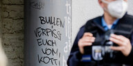 Polizist vor dem Schriftzug "Bullen verpisst euch vom Kotti"