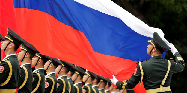 Sodlaten der chinesischen Ehrengarde hiehen eine russische Flagge auf