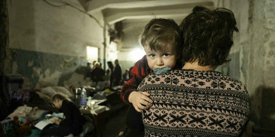 Eine Frau hält ihr Kind in einem Luftschutzbunker auf dem Arm