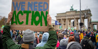 Ein Demonstrierender vor dem Brandenburger Tor hält ein Schild hoch mit der Aufschrift "We need Action"