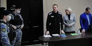 Nawalny mit seinen Anwält:innen und Uniformierten vor Gericht in einem Screenshot.