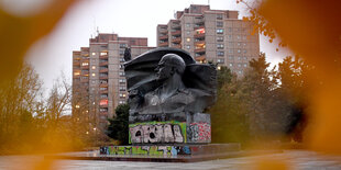 Ein Denkmal erinnert an Ernst Thälmann, dahinter Plattenbauten