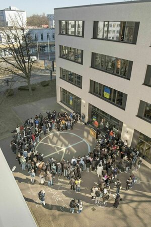 Schüler stehen um ein aufgemaltes Peace Zeichen im Schulhof herum Schüler stehen um ein aufgemaltes Peace Zeichen im Schulhof herum