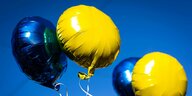 Blaue und gelbe Luftballons steigen in den Himmel.