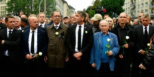 Politiker der AfD halten bei der Demonstration eine weiße Rose in der Hand