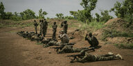 Bewaffnete Männer in Uniform liegen bäuchlings auf dem Boden