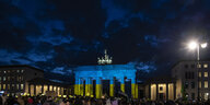 DDas Brandenburger Tor in Berlin wird am Abend bei einer Solidaritäts-Demonstration in den Farben der Ukraine angeleuchtet