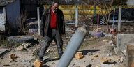 Ein Mann schaut in einem Wohnviertel auf eine eingeschlagene Rakete