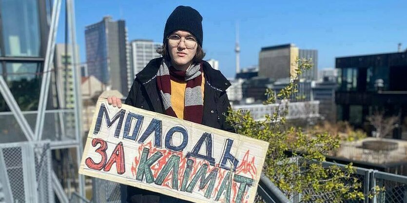 Eine junge Frau steht mit einem Plakat auf einer Dachterasse