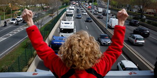 Eine Person jubelt vor einem LKW-Stau.