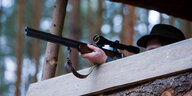 Ein Jäger im Hochsitz hat sein Gewehr angelegt