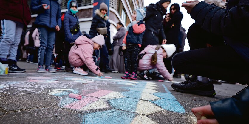 Kinder in einer Warteschlange malen mit Kreide auf den Boden