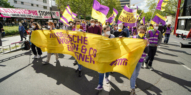 Eine Personengruppe protestiert mit gelb-violetten Bannern und Fahnen