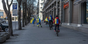 Kinder mit ukrainischen Fahnen auf dem Rücken fahren Fahrrad