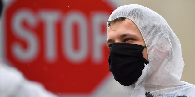 Ende Gelände Aktivist mit Maleranzug und Maske und Stop-Schild