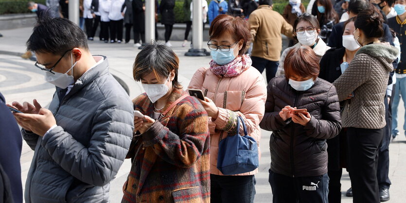 Personen mit Smartphones stehen in einer Schlange