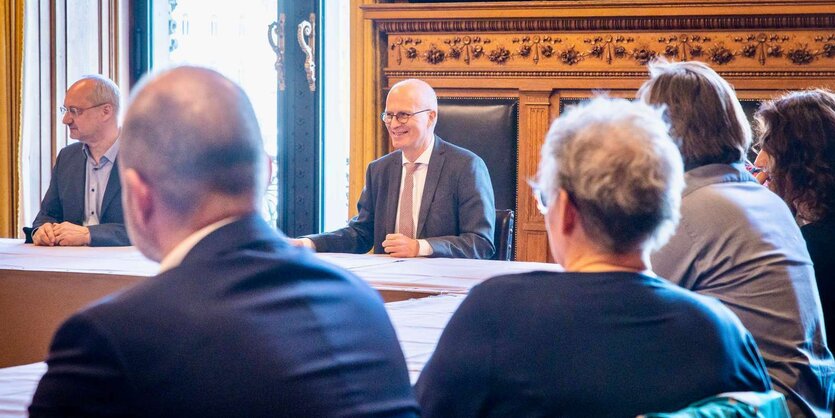 Menschen sitzen in großer Runde um einen Tisch herum