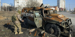 Soldat vor zerstörtem Militärfahrzeug