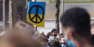 Klimastreik in Hamburg: EIn blau-gelbes Plakat mit Peace-Zeichen in der Menge