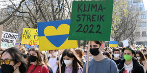 Junge Menschen auf Demo, im Vordergrund Demoschilder mit einem Herz in Ukraine-Farben und der Aufschrift 