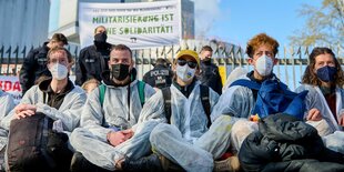 Menschen in weißen Anzügen sitzen vor einem Kraftwerk