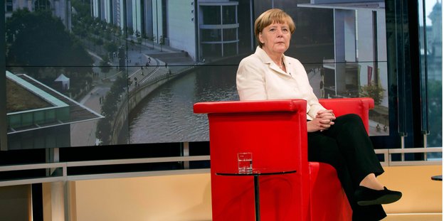 Angela Merkel sitzt in einem roten Sessel