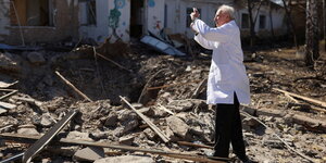 Ein Mann im Arztkittel fotografiert Trümmer