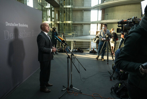 Ein Mann im Anzug steht im Bundestag und spricht in Mikrofone Ein Mann im Anzug steht im Bundestag und spricht in Mikrofone