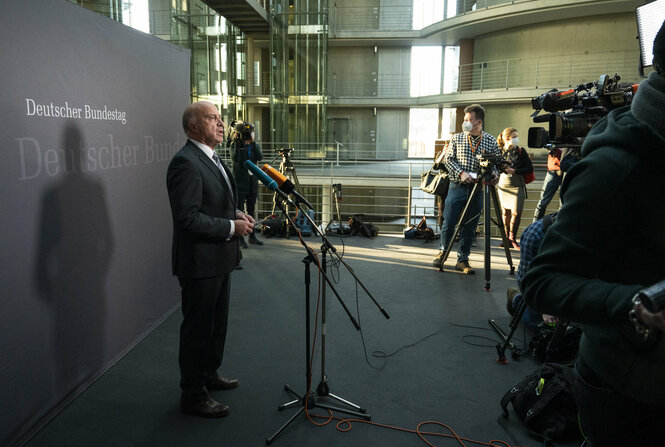 Ein Mann im Anzug steht im Bundestag und spricht in Mikrofone