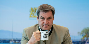 Söder hält eine Tasse in der Hand mit der Aufschrift "Alles wird gut"